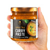Jar of Siam Yellow Thai Curry Paste held in a hand with a white background