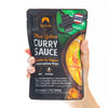 Hand holding a package of Siam Thai Yellow Curry Sauce on a white background